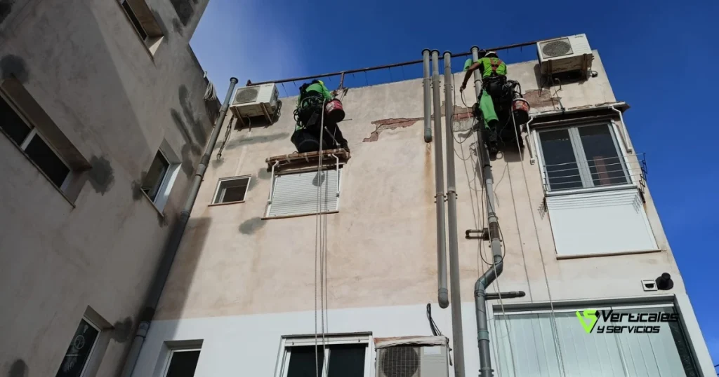 Operarios de Verticales y Servicios efectuando trabajos para impermeabilizar fachadas en comunidad de propietarios.