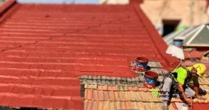 Operario realizando trabajos verticales sobre un tejado de teja rojiza, como ejemplo práctico dentro de los tipos de impermeabilización de cubiertas.