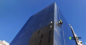 Operario de Verticales y Servicios ejecutando una tarea de limpieza de cristales en altura en un edificio.
