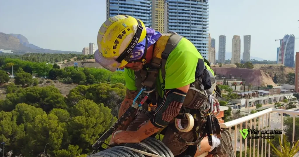 Operario de Verticales y Servicios efectuando un trabajo en altura con arnés.